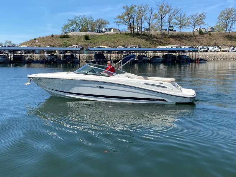 Slide: The Image of 2012 Sea Ray 270 SLX boat cruising on a calm lake near a marina. - 5