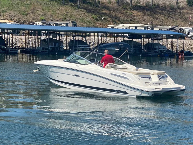Slide: The Image of 2012 Sea Ray 270 SLX boat cruising on a calm lake near a marina. - 7