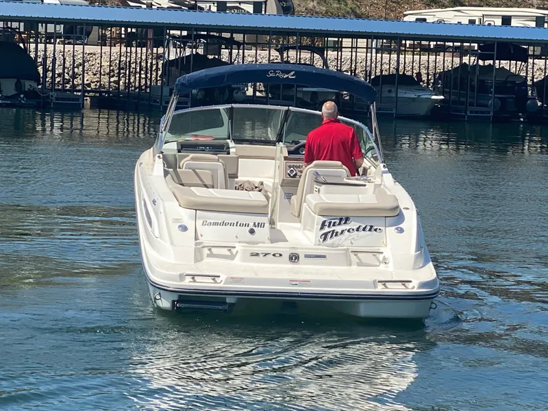 Slide: The Image of 2012 Sea Ray 270 SLX boat on water, man in red shirt steering. - 8