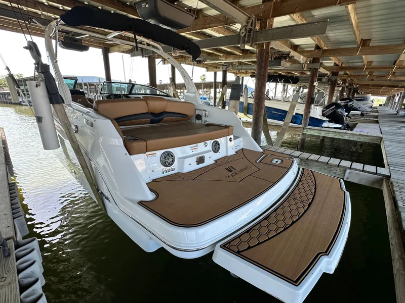 Slide: The Image of 2023 Four Winns HD8 boat docked, featuring spacious seating and elegant design. - 2