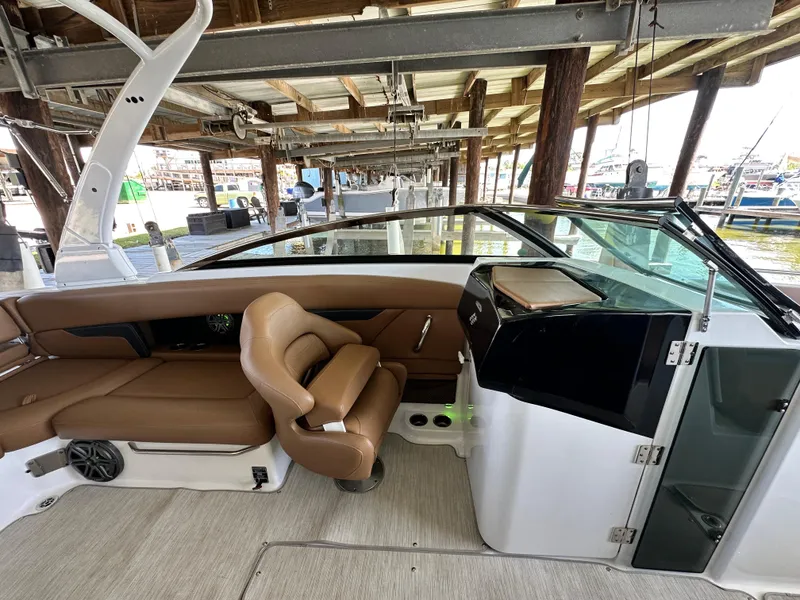 Slide: The Image of 2023 Four Winns HD8 boat interior with brown seating and modern dashboard. - 24