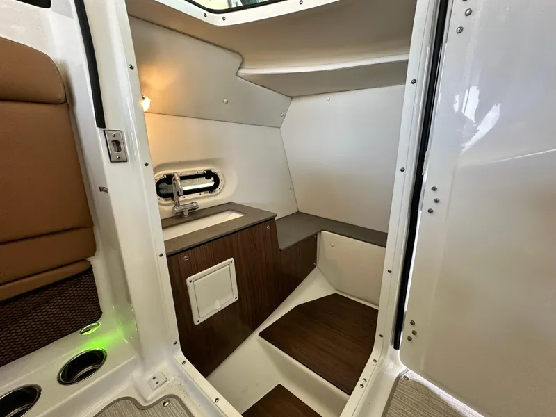 Slide: The Image of 2023 Four Winns HD8 boat interior with sink, wooden cabinetry, and seating area. - 25