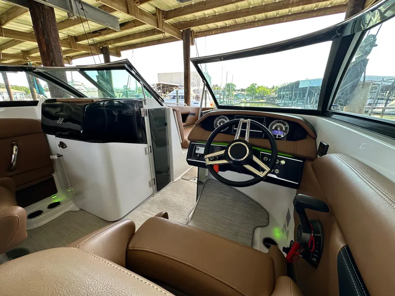 Slide: The Image of 2023 Four Winns HD8 boat interior with brown seating and modern dashboard. - 29