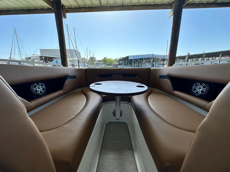 Slide: The Image of 2023 Four Winns HD8 boat interior with brown seating and round table, docked at marina. - 32