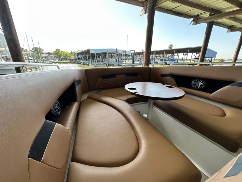 Slide: The Image of 2023 Four Winns HD8 boat interior with brown seating and round table at marina. - 33