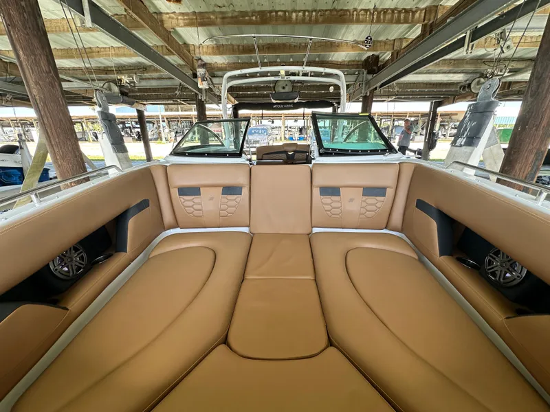 Slide: The Image of 2023 Four Winns HD8 boat interior with tan leather seating under a covered dock. - 38
