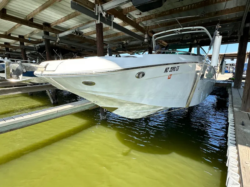 Slide: The Image of 2023 Four Winns HD8 boat docked in a marina, partially lifted above water. - 4