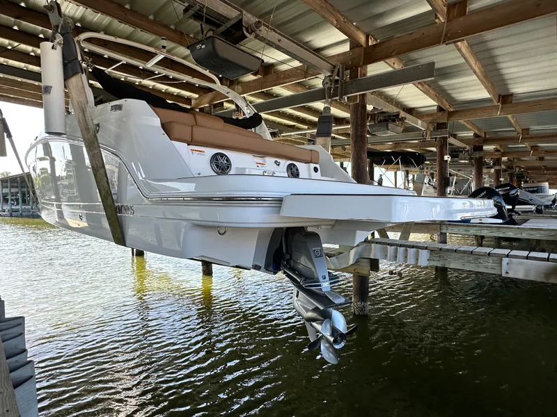 Slide: The Image of 2023 Four Winns HD8 boat docked in a covered marina, rear view. - 9
