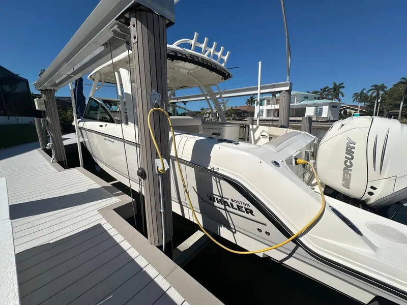 Slide: The Image of 2018 Boston Whaler 320 Vantage boat interior with seating, docked by a scenic waterfront. - 6