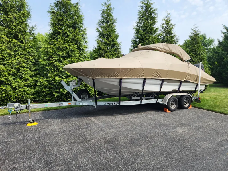 Slide: The Image of 2016 Crownline Eclipse E4 XS boat covered on a trailer, parked on a driveway. - 1
