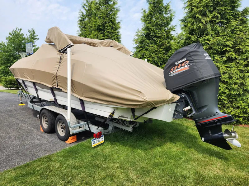 Slide: The Image of 2016 Crownline Eclipse E4 XS boat covered on trailer, parked on grass. - 5