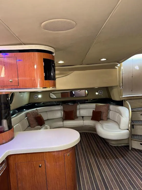 Slide: The Image of 1998 Sea Ray 500 Sundancer interior with curved seating, wood cabinetry, and modern lighting. - 15