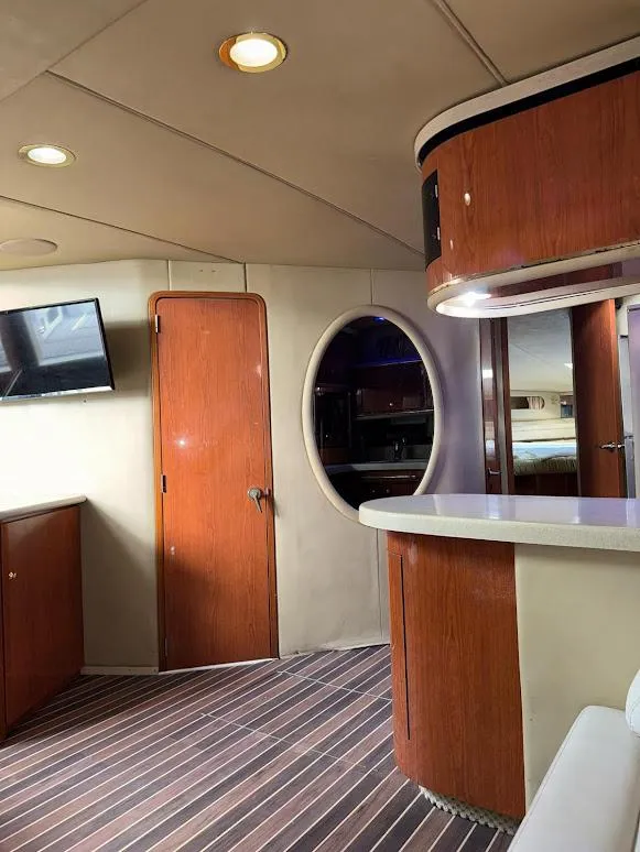 Slide: The Image of 1998 Sea Ray 500 Sundancer interior with wood accents, modern lighting, and a mounted TV. - 17