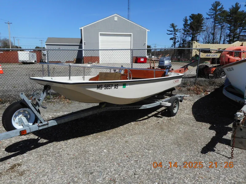 Slide: The Image of 1986 Boston Whaler 13 Super Sport boat on trailer, parked outdoors near a warehouse. - 1