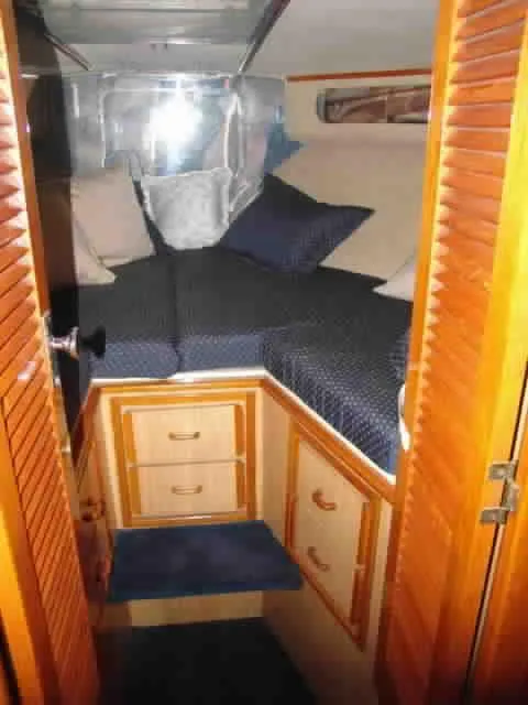Slide: The Image of 1983 Bertram Sportfisher cabin interior with wooden cabinetry and cozy bedding. - 11