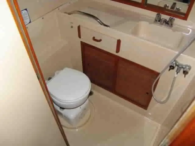 Slide: The Image of 1983 Bertram Sportfisher bathroom with toilet, sink, and wooden cabinetry. - 7