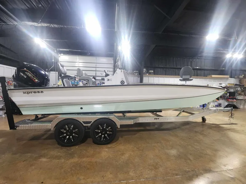 Slide: The Image of 2025 Xpress X23B Lounge boat on trailer in indoor showroom. - 0