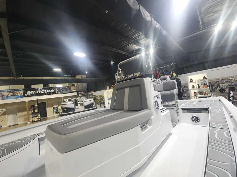 Slide: The Image of 2025 Xpress X23B Lounge boat interior with gray seating in showroom. - 6