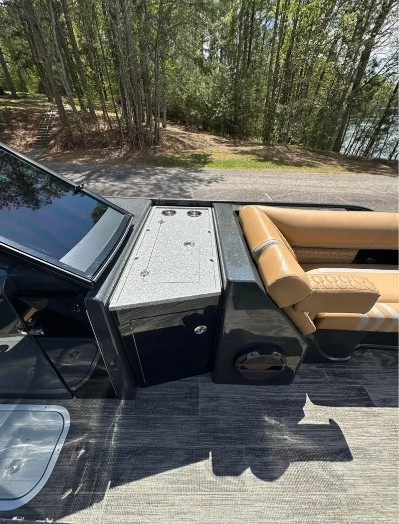 Slide: The Image of 2023 Crest Continental NX 270 boat interior with seating and console, surrounded by trees. - 15