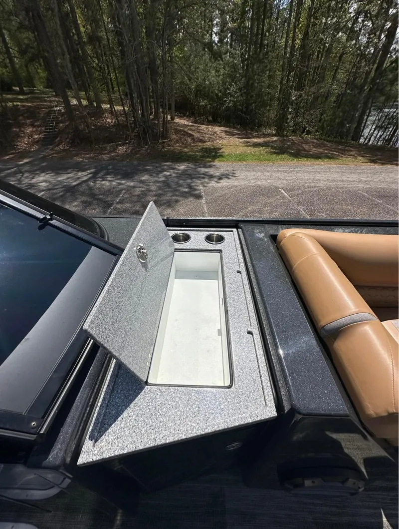 Slide: The Image of 2023 Crest Continental NX 270 boat with open storage compartment and cup holders. - 16