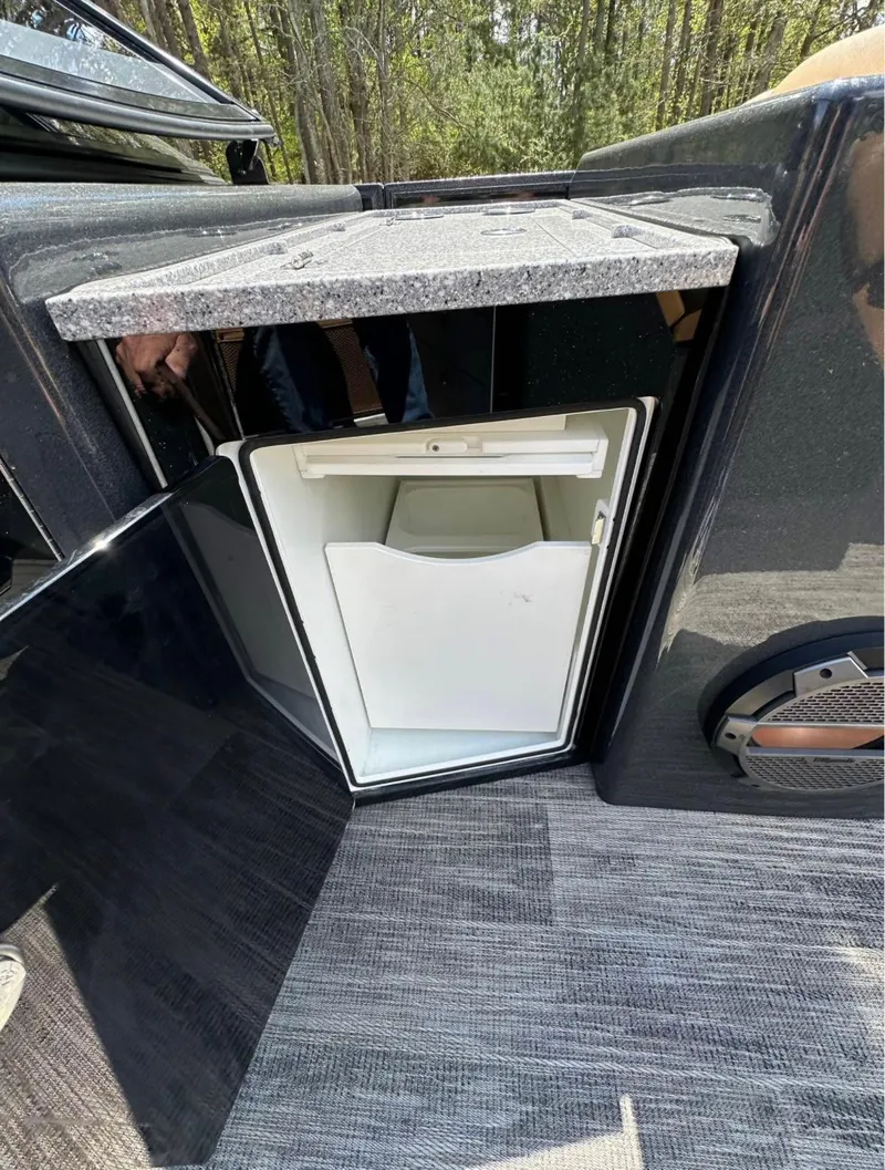 Slide: The Image of 2023 Crest Continental NX 270 boat with open mini fridge, outdoor setting. - 18