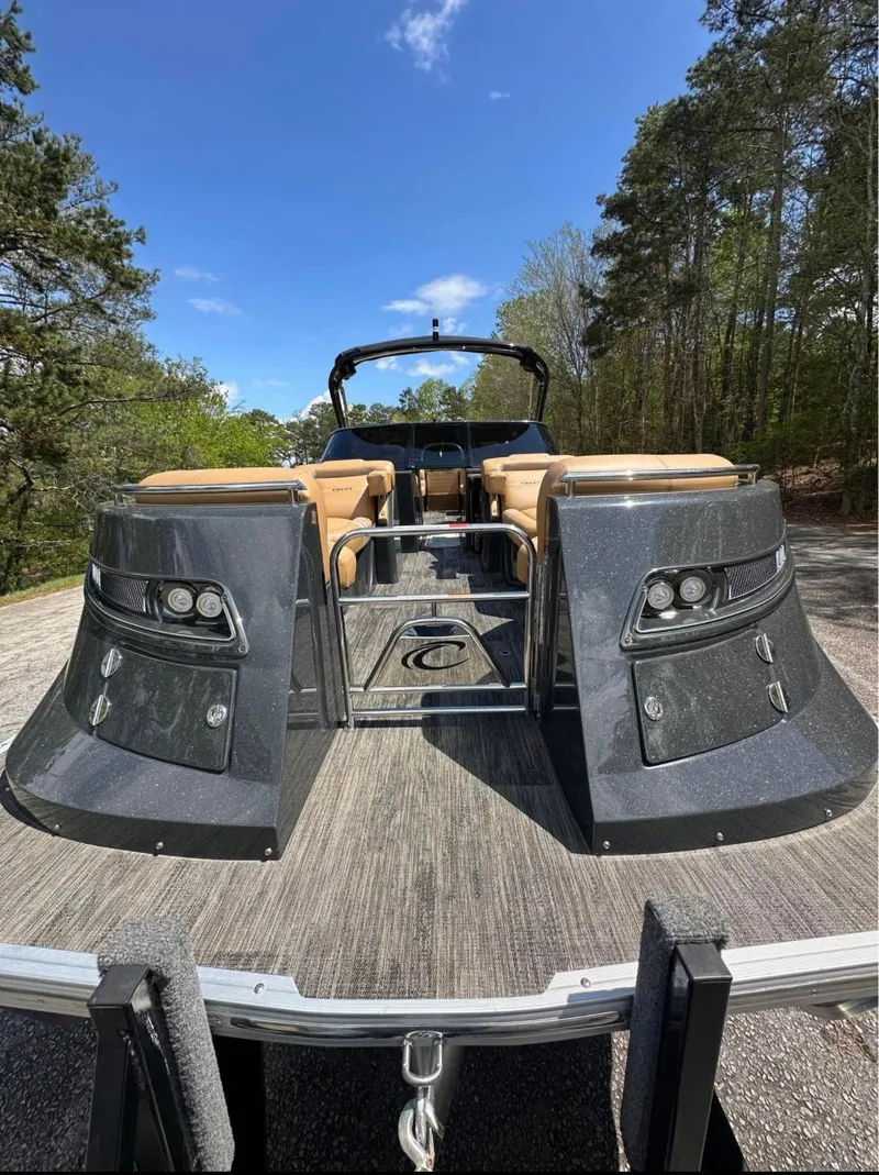 Slide: The Image of 2023 Crest Continental NX 270 boat with sleek design, parked outdoors under a clear blue sky. - 2