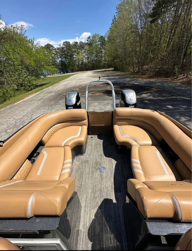 Slide: The Image of 2023 Crest Continental NX 270 boat with tan seating, parked on a scenic road. - 6