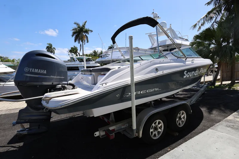 Slide: The Image of 2022 Regal 21 OBX boat on trailer with Yamaha outboard motor, docked near palm trees. - 14