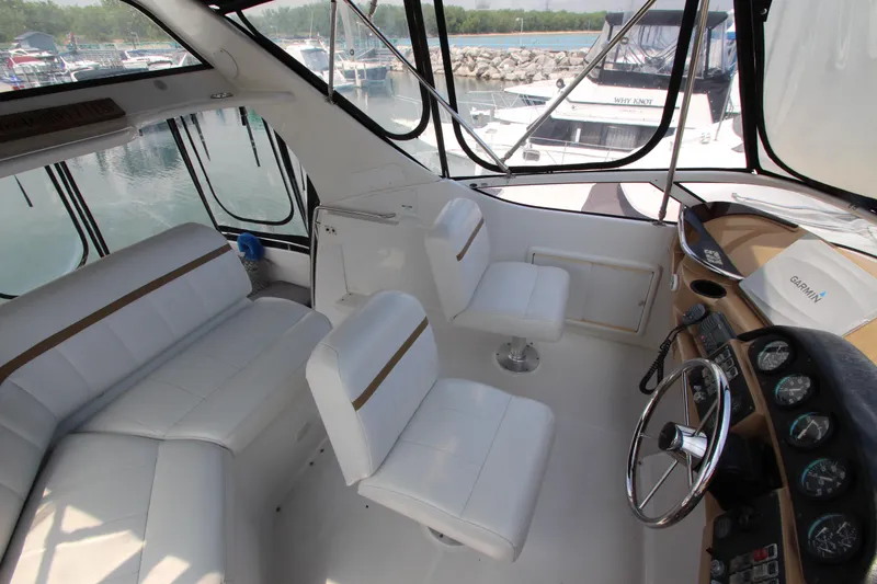 Slide: The Image of 2002 Carver 366 Motor Yacht interior with white seating and helm, docked at marina. - 14