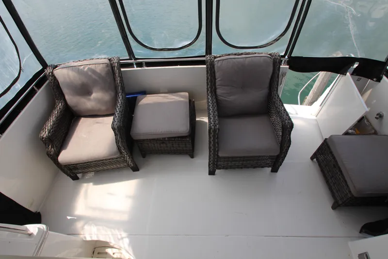 Slide: The Image of 2002 Carver 366 Motor Yacht deck with cushioned wicker chairs and ottomans. - 15