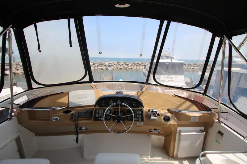 Slide: The Image of 2002 Carver 366 Motor Yacht helm with ocean view, featuring steering wheel and control panel. - 7