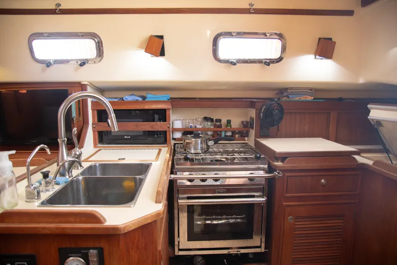 Slide: The Image of Interior of 1999 Island Packet 380 sailboat kitchen with sink, stove, and storage. - 12