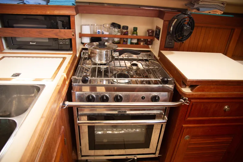 Slide: The Image of Galley kitchen in 1999 Island Packet 380 yacht with stove, oven, and wooden cabinetry. - 13