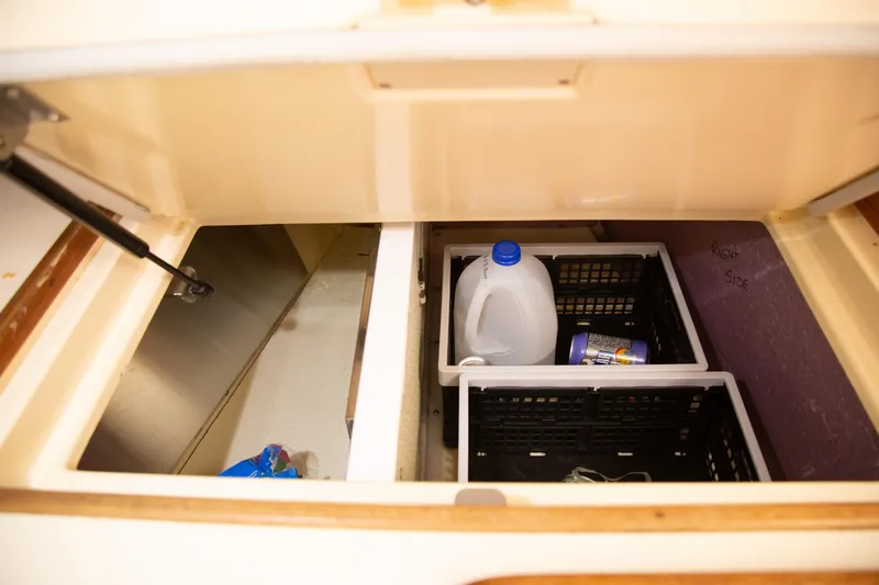 Slide: The Image of Storage compartment on a 1999 Island Packet 380 sailboat with crates and a water jug. - 21