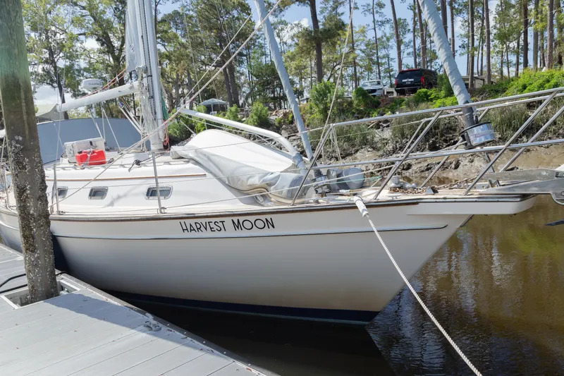 Slide: The Image of Island Packet 380 sailboat named "Harvest Moon" docked by a wooded shoreline. - 29