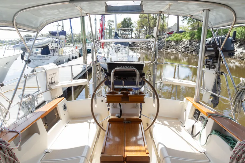Slide: The Image of 1999 Island Packet 380 sailboat cockpit with steering wheel, docked in a marina. - 30
