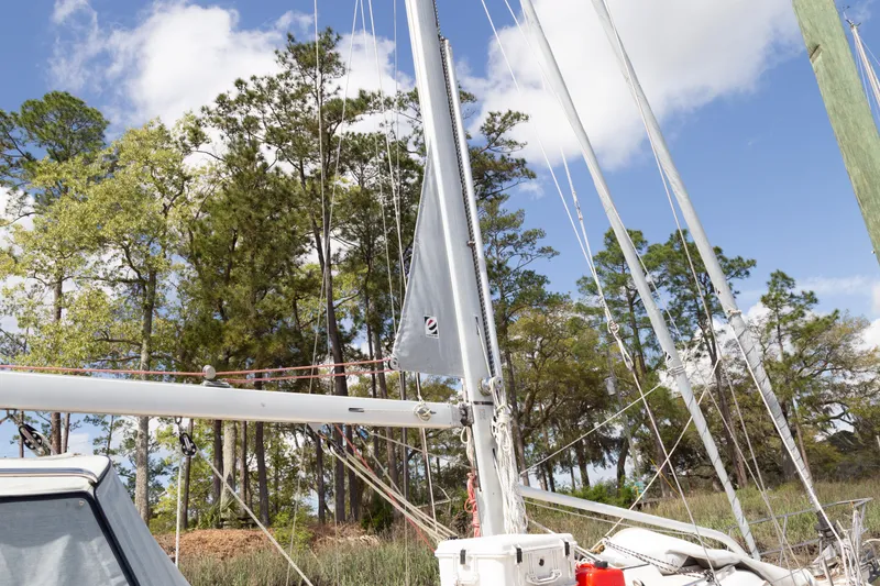 Slide: The Image of Sailboat Island Packet 380, 1999 model, docked near lush trees under a blue sky. - 42
