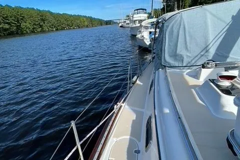 Slide: The Image of 1999 Island Packet 380 sailboat docked on a serene river with lush greenery. - 43