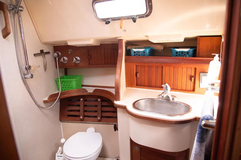 Slide: The Image of Island Packet 380 yacht bathroom, 1999 model, featuring sink, toilet, shower, and wooden cabinetry. - 8