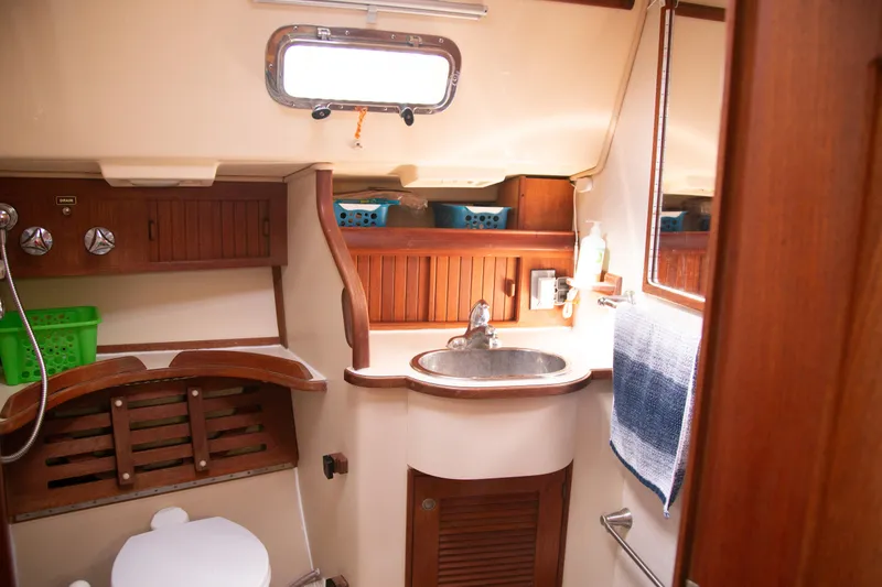 Slide: The Image of Interior of 1999 Island Packet 380 sailboat bathroom with sink, toilet, and wooden cabinetry. - 9