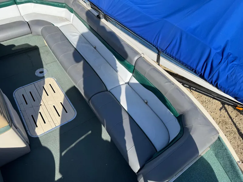 Slide: The Image of 1999 Sun Tracker Party Deck 21 boat seat with gray upholstery and fire extinguisher nearby. - 12
