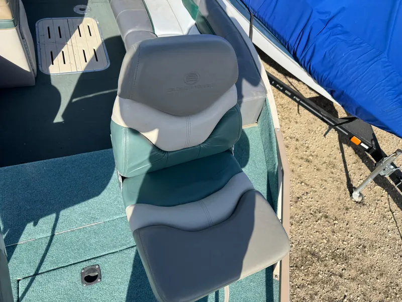 Slide: The Image of 1999 Sun Tracker Party Deck 21 boat seating with gray, green, and white upholstery. - 15