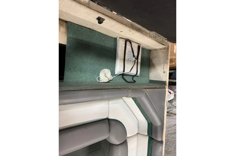 Slide: The Image of 1999 Sun Tracker Party Deck 21 interior with storage compartment and coiled rope. - 18