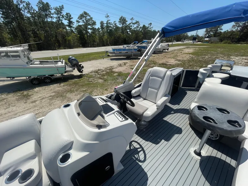Slide: The Image of 2017 Godfrey 255 Sweetwater Premium pontoon boat with seating and steering console, parked outdoors. - 21