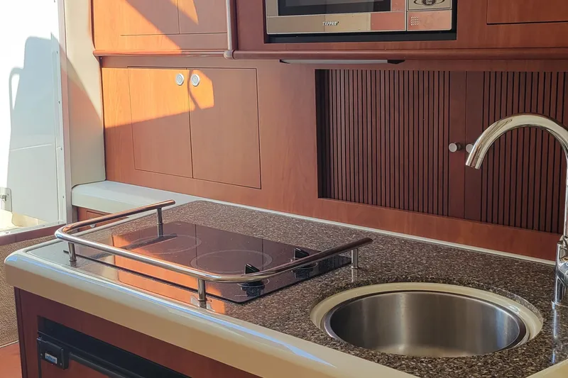 Slide: The Image of 2008 Monterey 315 Sport Yacht kitchen with stove, sink, and microwave in wooden cabinetry. - 9