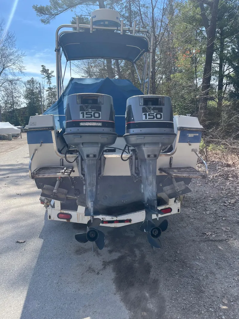 Slide: The Image of 1989 Wellcraft 250 Sportsman boat with dual 150 horsepower outboard motors, parked on a sunny day. - 13