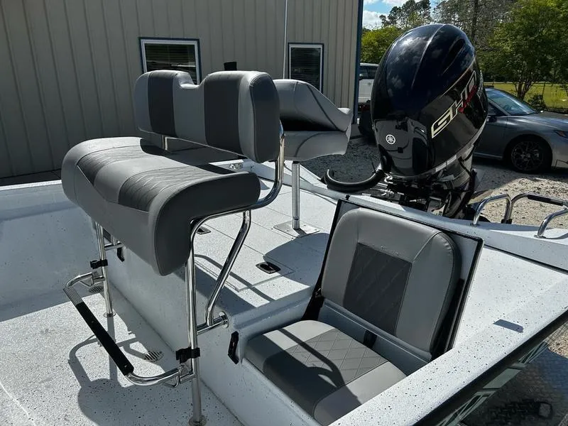 Slide: The Image of 2025 Xpress H22B boat interior with seating and motor, parked outdoors. - 14