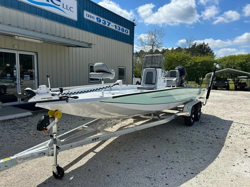 Slide: The Image of 2025 Xpress H22B boat on trailer outside dealership under blue sky. - 2