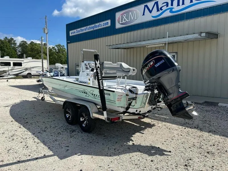 Slide: The Image of 2025 Xpress H22B boat with Yamaha motor, parked outside a marine dealership. - 4