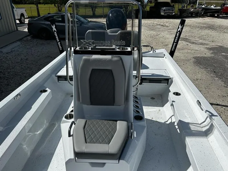 Slide: The Image of 2025 Xpress H22B boat interior with gray seating and console, parked outdoors. - 7
